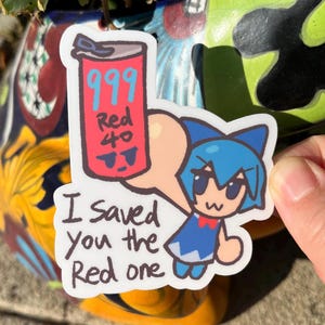 May include: A sticker featuring a cartoon character with blue hair and a red bow tie, holding a speech bubble with a red can that says "999 Red 40". The text on the sticker reads "I saved you the Red one".