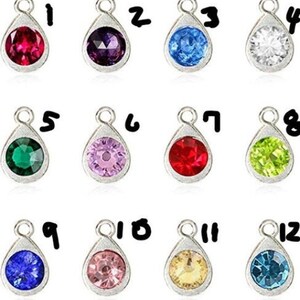 May include: Twelve silver teardrop-shaped charms with different colored rhinestones. The charms are numbered 1 through 12.