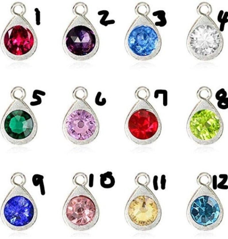 May include: Twelve silver teardrop-shaped charms with different colored rhinestones. The charms are numbered 1 through 12.