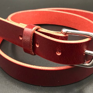 Full Grain Genuine Leather Belt in Red Color with Silver Buckle. The edges are finished and dyed to match the main leather color. The buckle is buckle and the tail place through the keeper. Chicago Screws hold the buckle onto the leather strap.