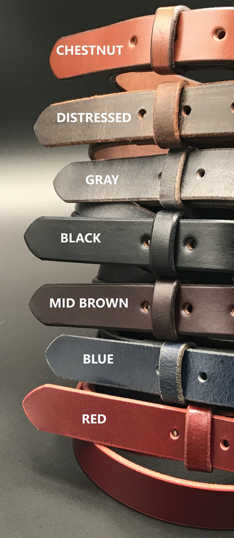 K&ouml;nnte beinhalten: Ein Stapel von sieben Lederg&uuml;rteln in verschiedenen Farben, darunter Kastanie, Used Look, Grau, Schwarz, Mittelbraun, Blau und Rot. Jeder G&uuml;rtel hat ein spitzes Ende und ein einzelnes Loch f&uuml;r eine Schnalle.