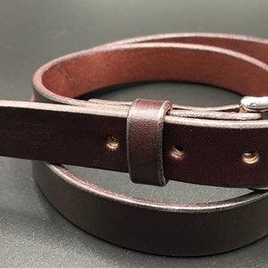 Full Grain Genuine Leather Belt in Brown Color with Silver Buckle. The edges are finished and dyed to match the main leather color. The buckle is buckle and the tail place through the keeper. Chicago Screws hold the buckle onto the leather strap.