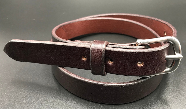 Full Grain Genuine Leather Belt in Brown Color with Silver Buckle. The edges are finished and dyed to match the main leather color. The buckle is buckle and the tail place through the keeper. Chicago Screws hold the buckle onto the leather strap.