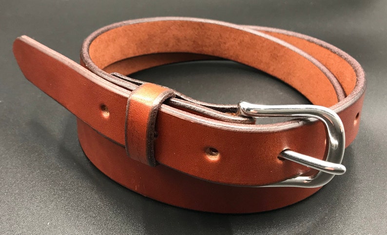 Full Grain Genuine Leather Belt in Chestnut Color with Silver Buckle. The edges are finished and dyed to match the main leather color. The buckle is buckle and the tail place through the keeper. Chicago Screws hold the buckle onto the leather strap.