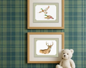 May include: Two framed watercolor prints with a nature theme. One print features two ducks in flight, and the other depicts a deer. The frames are light brown, and the background is a green and white gingham pattern. A white teddy bear sits on a wooden surface.