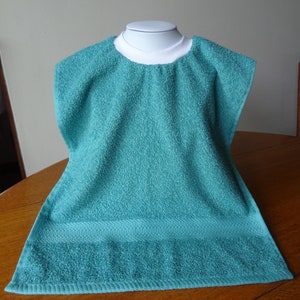 May include: A teal blue terry cloth bib with a white trim around the neck.