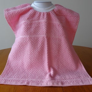 Pullover pink toddler towel bib with white ribbed neck.