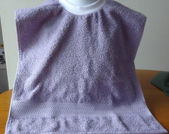 May include: A lavender-colored terry cloth bib with a white trim around the neck opening. The bib has a decorative border at the bottom.