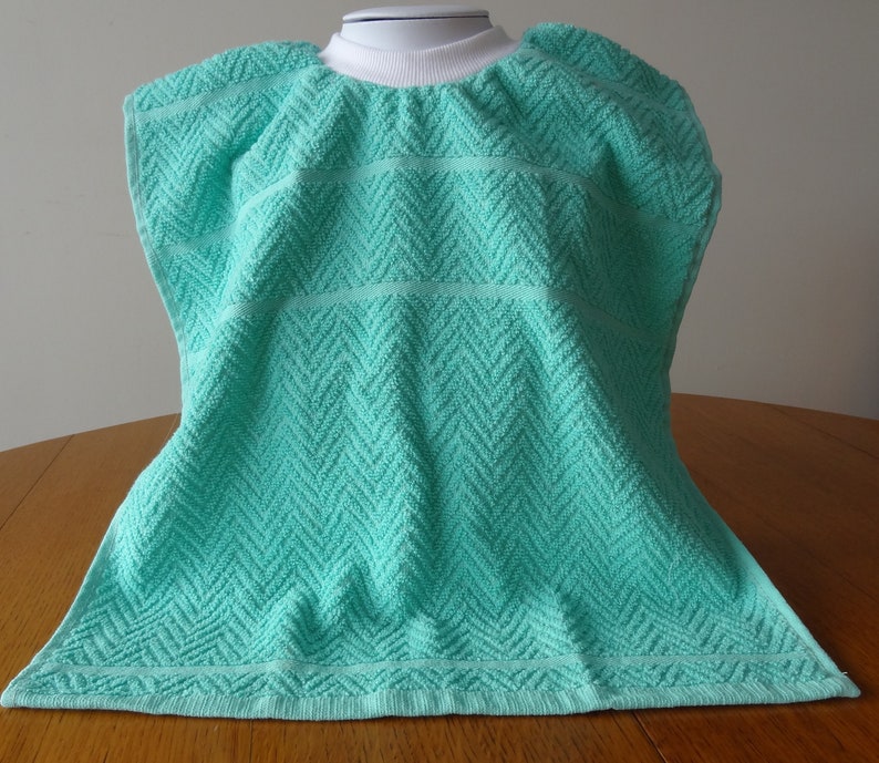 Pullover aqua toddler towel bib with white ribbed neck.