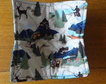 May include: A square, quilted pot holder with a camping theme. The fabric features a beige background with a repeating pattern of green trees, blue mountains, deer, campers, and fishing scenes. The pot holder has a green border.