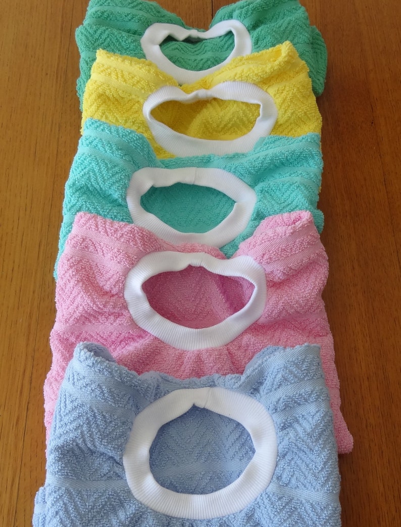 Pullover towel bibs for toddlers in blue, green, pink and yellow and aqua with white ribbed neck.