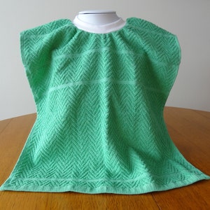 Pullover green toddler towel bib with white ribbed neck.