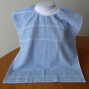 Pullover blue toddler towel bib with white ribbed neck.