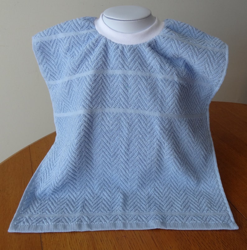 Pullover blue toddler towel bib with white ribbed neck.