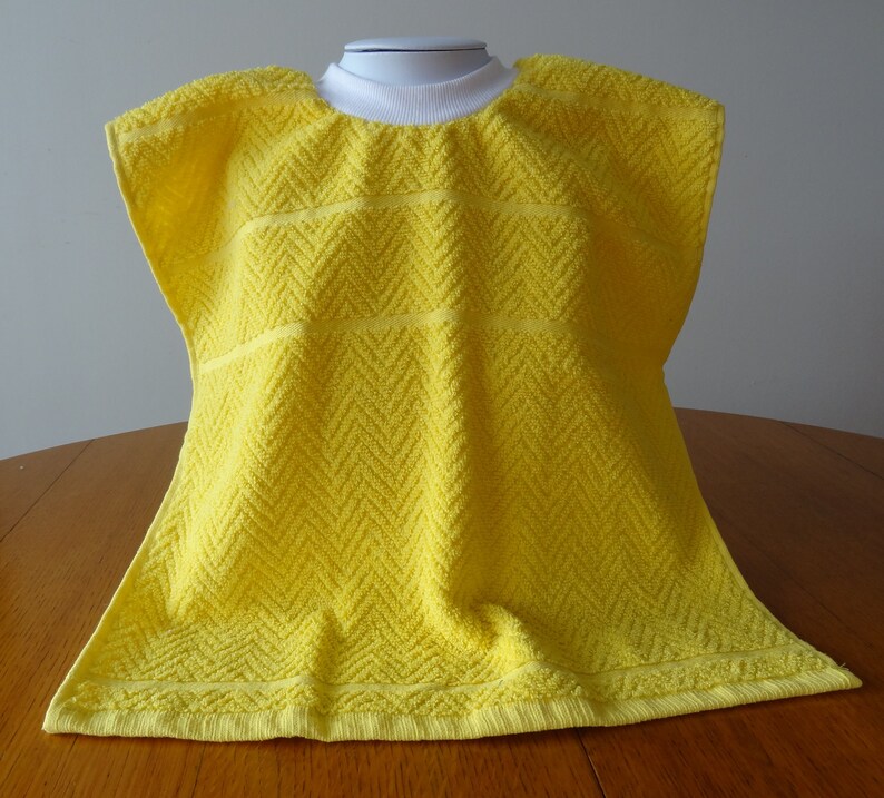 Pullover yellow toddler towel bib with white ribbed neck.
