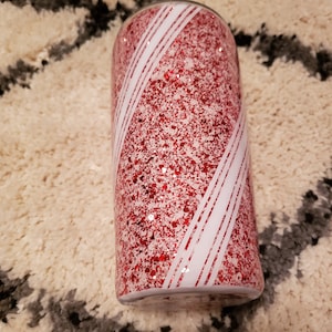 May include: A red and white glitter tumbler with a candy cane design.