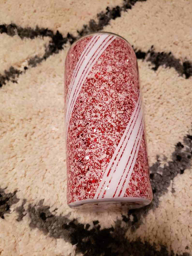 May include: A red and white glitter tumbler with a candy cane design.