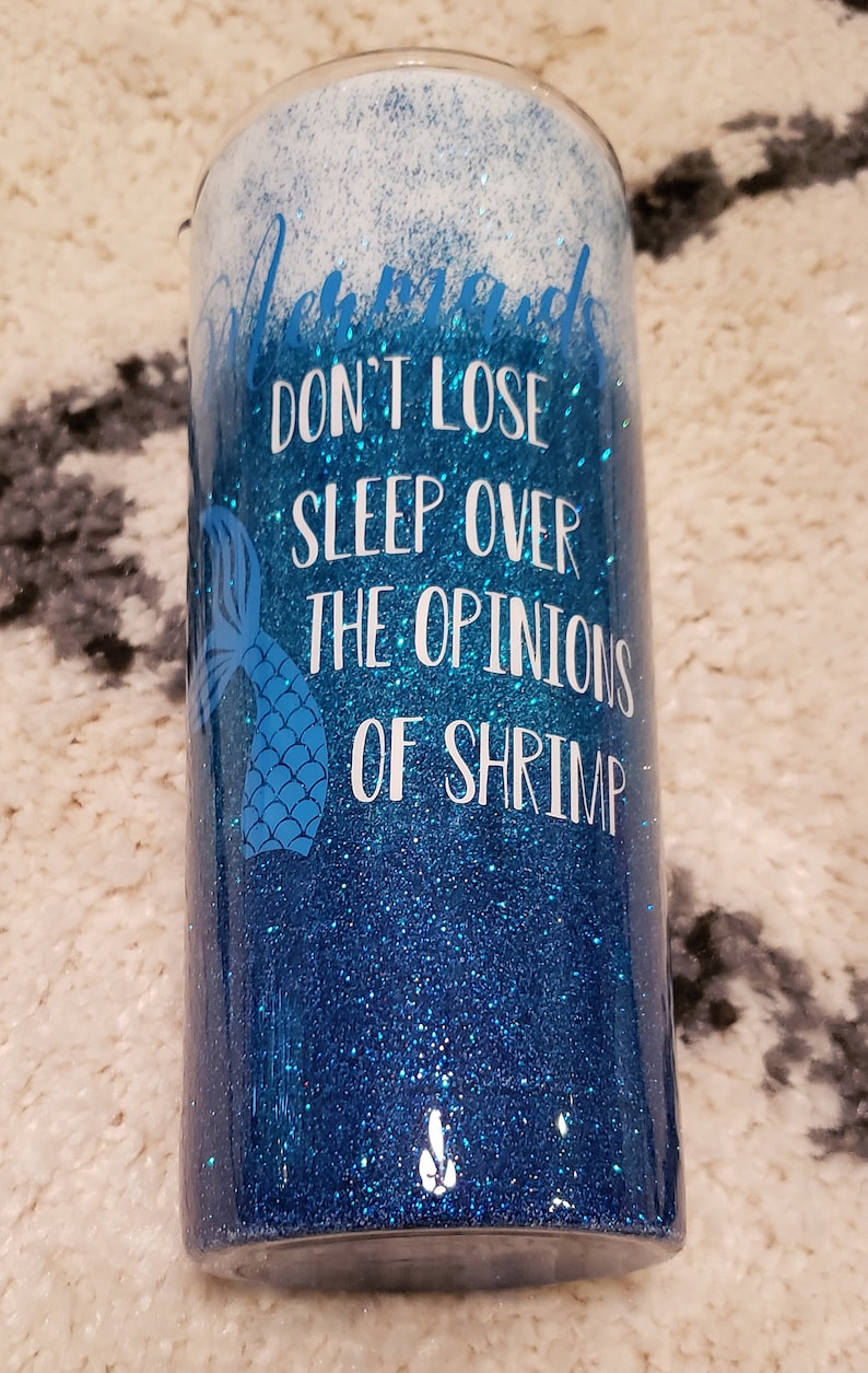 May include: A blue and white glitter tumbler with a mermaid tail and the text "Don't lose sleep over the opinions of shrimp".