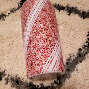 May include: A red and white glitter tumbler with a candy cane design.