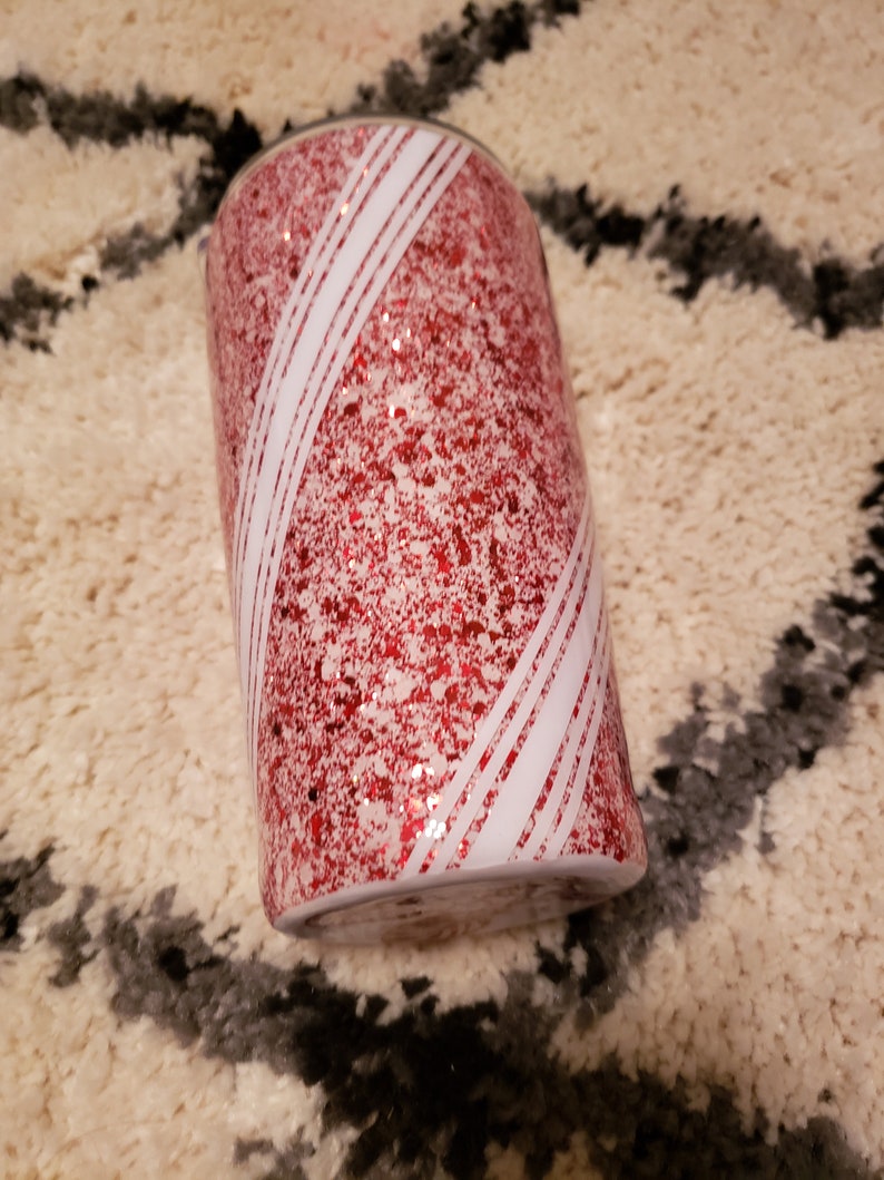 May include: A red and white glitter tumbler with a candy cane design.