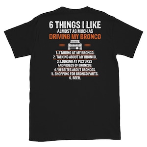 May include: Black t-shirt with white text that reads "6 Things I Like Almost As Much As Driving My Bronco". A small black and white image of a Ford Bronco is above the text. The text continues with a list of six things: "1. Staring at my Bronco. 2. Talking about my Bronco. 3. Looking at pictures and videos of Broncos. 4. Websites about Broncos. 5. Shopping for Bronco parts. 6. Beer."