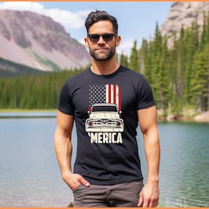 May include: A black t-shirt with a vintage American flag and a classic pickup truck graphic. The text 'MERICA' is printed below the truck.
