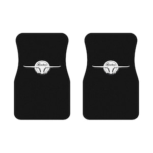 May include: Two black car floor mats with a silver Ford Ranchero logo featuring a bull's head.