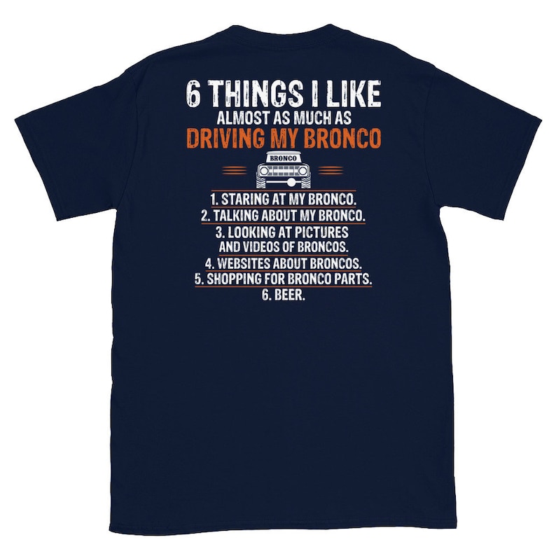May include: A navy blue t-shirt with a white graphic of a Ford Bronco and the text "6 THINGS I LIKE ALMOST AS MUCH AS DRIVING MY BRONCO". The text below the graphic lists six things the wearer likes almost as much as driving their Bronco: "1. STARING AT MY BRONCO. 2. TALKING ABOUT MY BRONCO. 3. LOOKING AT PICTURES AND VIDEOS OF BRONCOS. 4. WEBSITES ABOUT BRONCOS. 5. SHOPPING FOR BRONCO PARTS. 6. BEER."