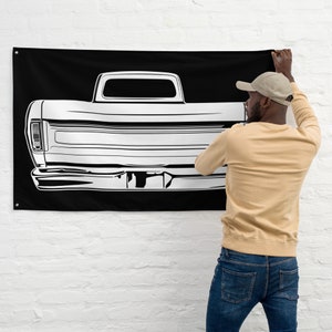 May include: A black and white flag with a silhouette of a vintage pickup truck. The truck is facing away from the viewer and is outlined in white against a black background.