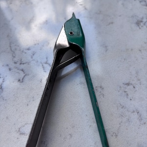 May include: A metal and green staple remover tool. The tool has a pointed tip and a hinged design for removing staples. The handle is green, and the rest of the tool is silver.