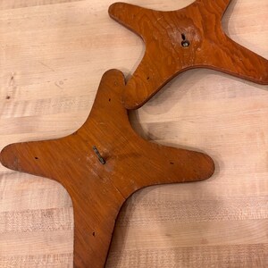 May include: Two wooden star-shaped bases with a hole in the center. The bases are brown and have a smooth finish.