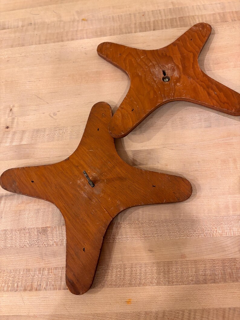 May include: Two wooden star-shaped bases with a hole in the center. The bases are brown and have a smooth finish.