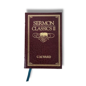 May include: A maroon-colored book titled "SERMON CLASSICS II" with gold lettering and accents. The author's name, C.M. WARD, is printed at the bottom. A teal ribbon bookmark is visible.