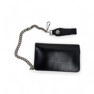 May include: A black leather wallet with a silver chain and a snap closure. The wallet is rectangular and has a smooth surface. The chain is attached to the wallet and a leather loop with a snap.