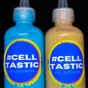 K&ouml;nnte beinhalten: Zwei Flaschen blauer und goldener Farbe mit #CellTastic Cell Activator Etiketten. Die blaue Flasche ist mit "Aztec Blue" und die goldene Flasche mit "Glam Gold" beschriftet.