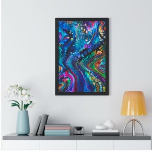 Op de afbeelding: Abstracte kunstprint met draaiende blauwe, groene, paarse en roze verf in een zwart frame.