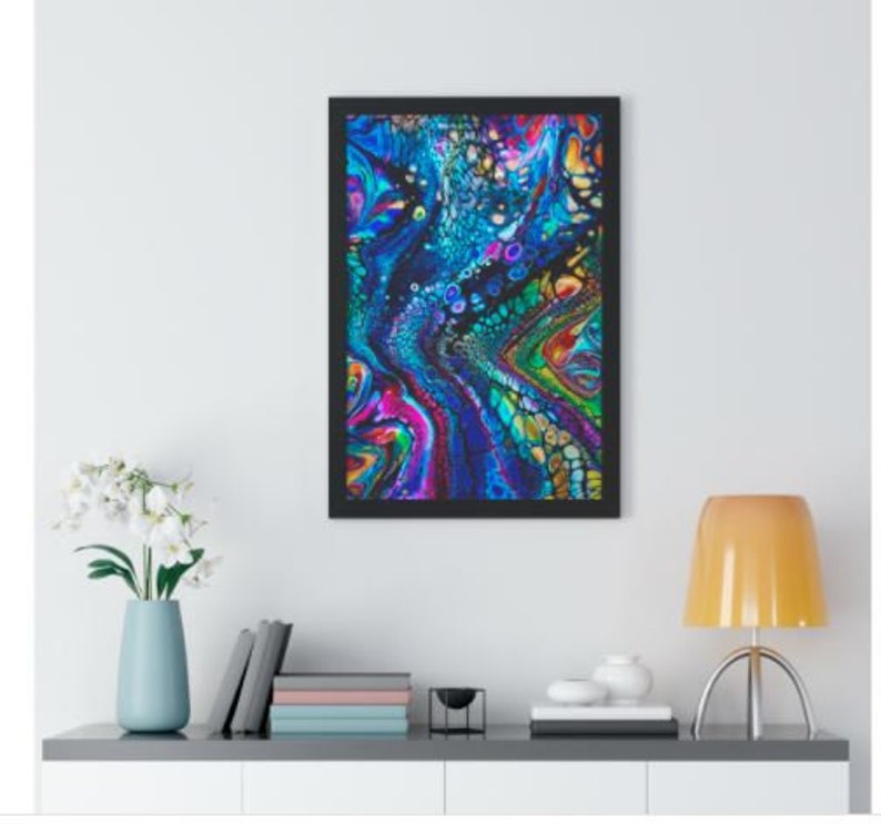 Op de afbeelding: Abstracte kunstprint met draaiende blauwe, groene, paarse en roze verf in een zwart frame.