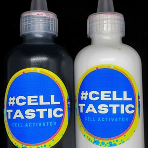 K&ouml;nnte beinhalten: Zwei Flaschen #CellTastic Zell Aktivator, eine in Rabenschwarz und eine in Arktiswei&szlig;. Die Flaschen haben ein blaues und gelbes Etikett mit dem Text #CellTastic Zell Aktivator.
