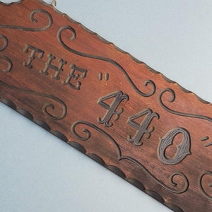 May include: A wooden sign with a carved design and the text "THE "440"" in black lettering.