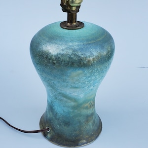 May include: A turquoise ceramic table lamp with a textured surface and a brass base. The lamp has a standard light bulb socket and a cord with a plug.