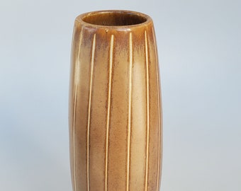 May include: A tall, brown ceramic vase with vertical, cream-colored stripes. The vase has a rounded, cylindrical shape and a smooth, glossy finish. The stripes add a decorative element to the vase, which is suitable for displaying flowers or as a decorative accent.