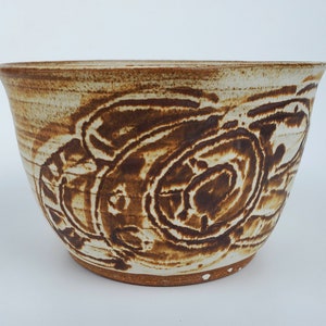 May include: A white ceramic bowl with a brown swirl design. The bowl is handmade and has a rustic look.