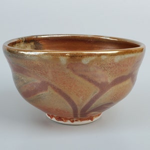 May include: A ceramic bowl with a brown, orange, and gray glaze. The bowl has a rounded shape and a slightly flared rim.