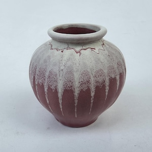 May include: A round, ceramic vase with a wide opening. The vase is a deep burgundy color with a white, dripped glaze effect. The rim is a light gray color. This decorative vase is suitable for home decor.
