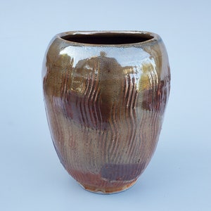 May include: A ceramic vase with a brown and gold glaze. The vase has a wavy, textured surface.
