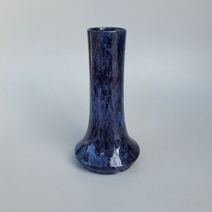 May include: A blue ceramic vase with a mottled glaze. The vase has a wide base and a narrow neck.