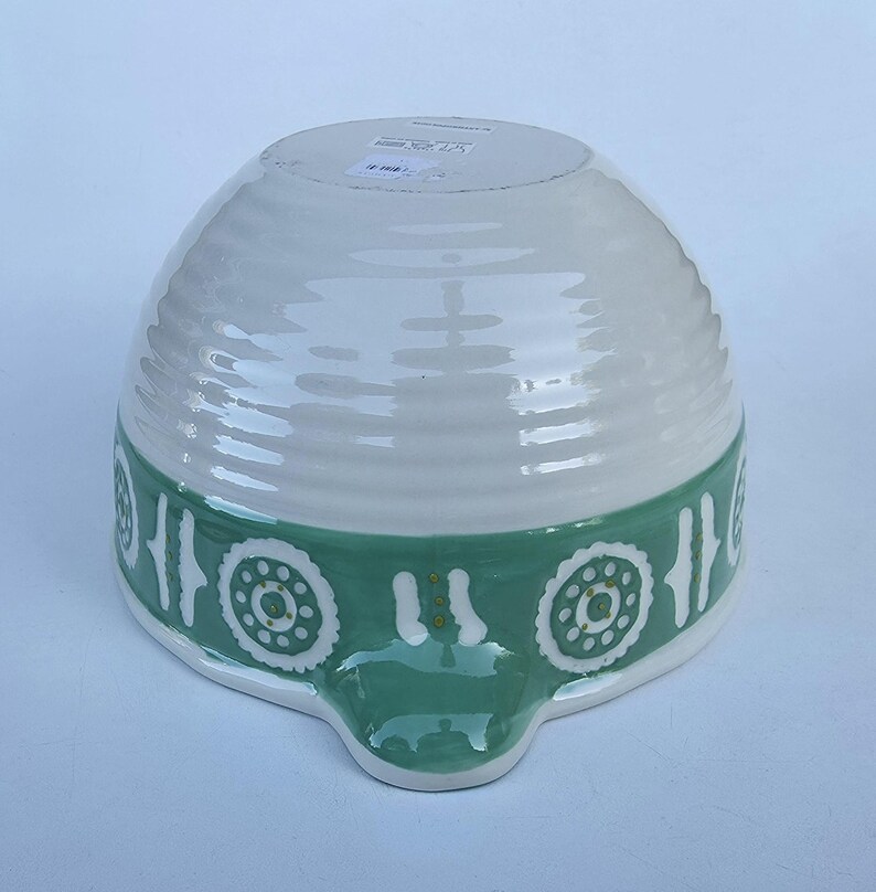 Peut inclure: Bol &agrave; m&eacute;langer en c&eacute;ramique blanche et verte. Le bol a une forme arrondie avec une base large et un bec verseur. La moiti&eacute; sup&eacute;rieure est blanche et la moiti&eacute; inf&eacute;rieure est verte avec un motif d&eacute;coratif. Le bol mesure environ 20 cm de diam&egrave;tre.