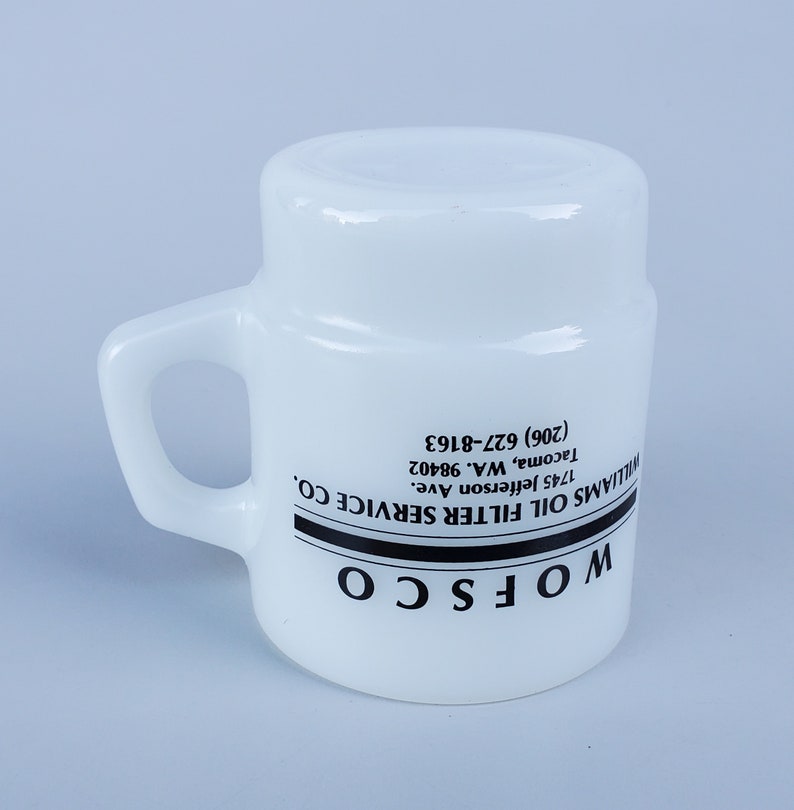 May include: White ceramic mug with a black handle and black text that reads "WOFSCO WILLIAMS OIL FILTER SERVICE CO. 1745 Jefferson Ave. Tacoma, WA. 98402 (206) 627-8163"