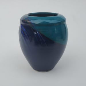 May include: A small, blue and teal ceramic vase with a swirl design. The vase is glazed and has a smooth finish.