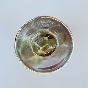May include: The underside of a clear glass bowl with a swirling pattern. The bowl is signed "The Glass Forge 2003".
